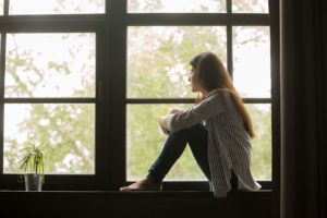 Image of a woman staring out of the window. If you're feeling isolated and looking for support, CBT Therapy in Reading, PA could be just what you need to start feeling better! 