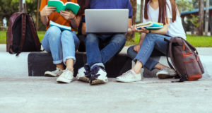 Image of teens sitting together looking at a laptop and books. Showing one of the stresses that a counselor for a teenager can help with. In teen counseling they can get support and understanding in Reading, Wyomissing, or Exeter, PA.