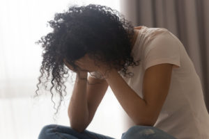 Image of a woman with her head down in her hands. Showing someone suffering from anxiety symptoms in Reading, PA. Who could benefit from therapy for anxiety treatment.