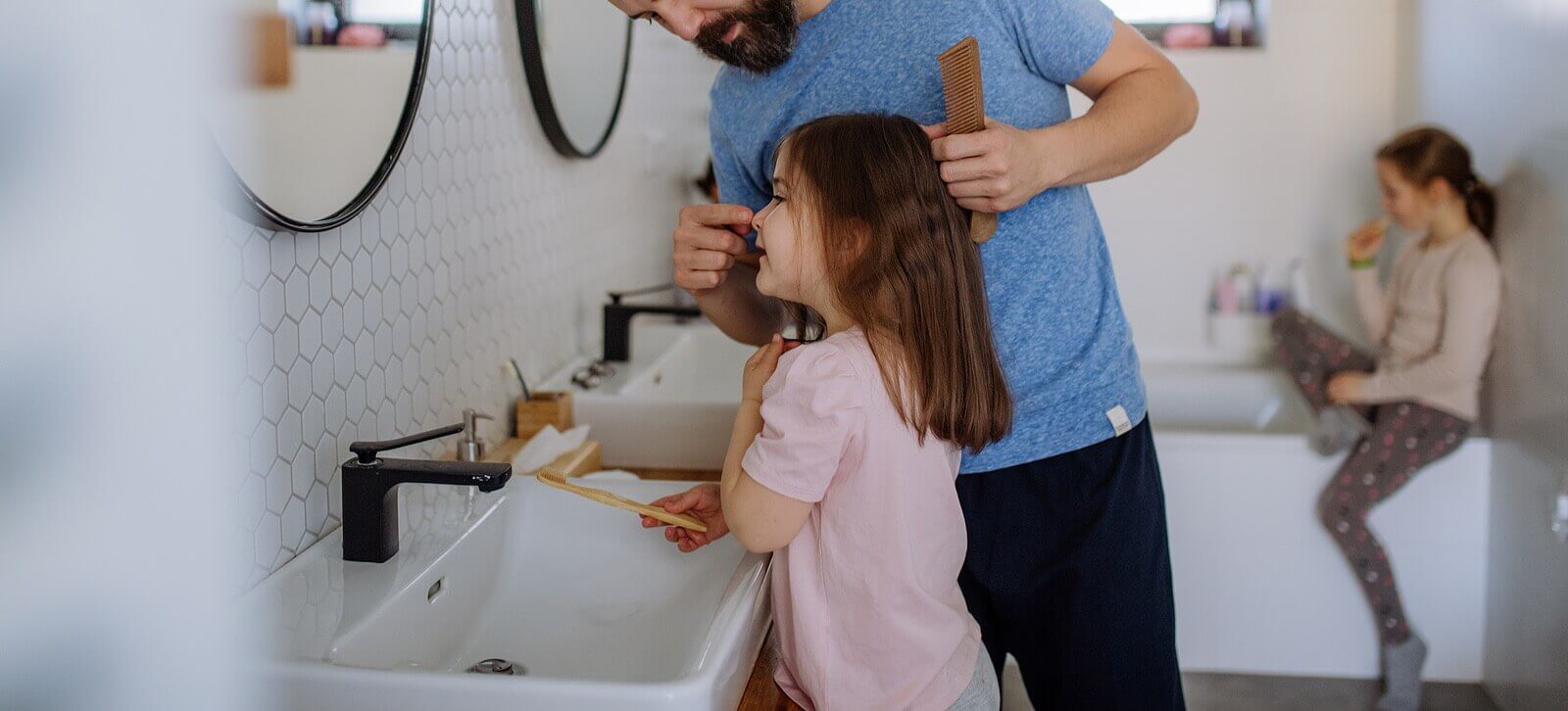 Image of a dad doing his daughters hair in the bathroom. Showing that connection that can be formed in family therapy in Reading, PA. A family therapist can improve the bond of parent and child in family counseling whether in Wyomissing, Reading, or anywhere in Pennsylvania.