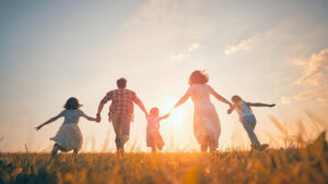 Image of a family of 5 running in a field. Representing the benefits of ADHD family counseling in Reading, PA. With support of a family therapist in Wyomissing, Pennsylvania you can have this bond with your loved ones.